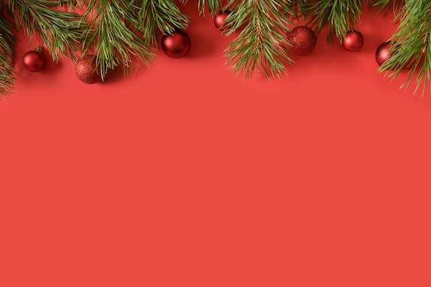 Bannière de Noël avec décor rouge et branches de sapin à feuilles persistantes sur fond rouge. Vue de dessus. Carte de voeux de Noël.