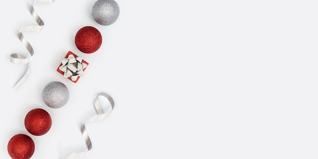 Bannière de Noël avec des décorations de boules lumineuses, des boules de couleur rouge et argent et une boîte-cadeau