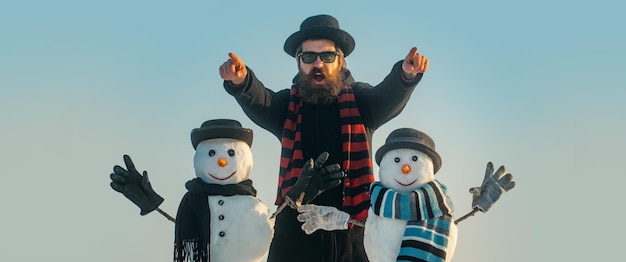 Bannière de Noël drôle hiver bonhomme de neige au chapeau jouer avec bonhomme de neige homme en plein air avec bonhomme de neige en hiver o