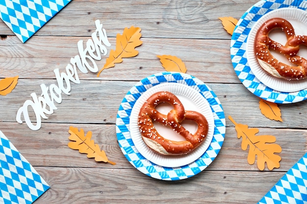 Bannière Oktoberfest avec espace de texte, main tenant des bretzels et des décorations bleu-blanc