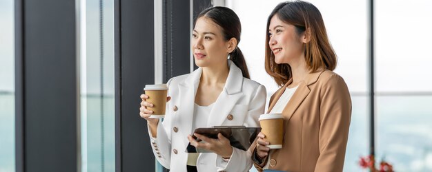 Bannière, page Web ou modèle de couverture de deux femmes d'affaires asiatiques parlant pendant la pause-café dans un bureau moderne