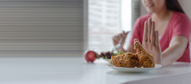 Bannière panoramique. Régime. jeune femme jolie refuser le poulet frit, la malbouffe ou la nourriture malsaine et manger des salades de légumes frais pour une bonne santé à la maison