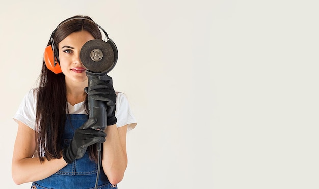 Bannière avec Portrait d'une femme souriante sur un chantier de construction tenant une scie à meuler, espace de copie