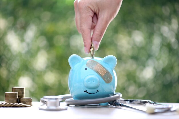 Photo banque de cochons attachée au plâtre sur la tête et stéthoscope sur fond vert économisez de l'argent pour l'assurance maladie et le concept de soins de santé