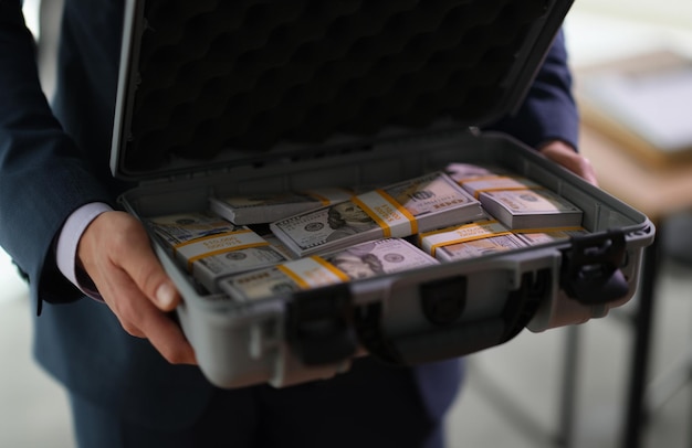 Banquier tenant une valise avec beaucoup de billets de dollar en gros plan