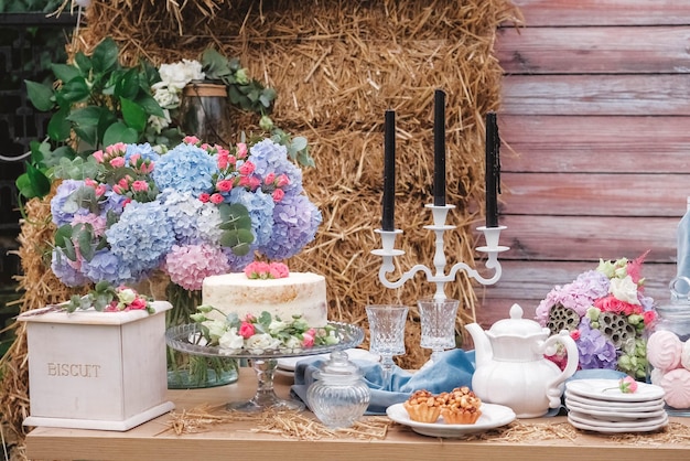 Bar à bonbons de mariage de style rustique décoré d'assiettes couverts verres bougies