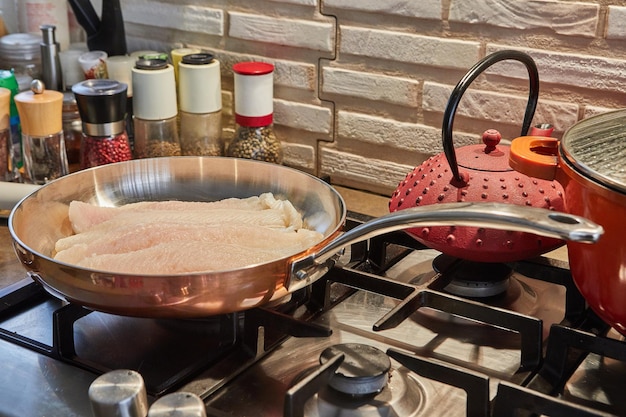 Le bar est frit dans une casserole en cuivre sur un poêle à gaz.