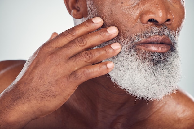 Barbe et visage à la main avec un homme noir âgé se toilettant en studio sur fond gris pour la beauté ou les soins de la peau Hygiène de la peau et cosmétiques avec un homme mature à l'intérieur pour favoriser l'entretien des poils du visage