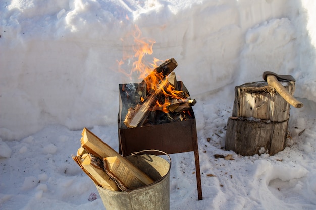 Barbecue à bois en hiver dans la rue. Vacances en famille. Faire frire les brochettes