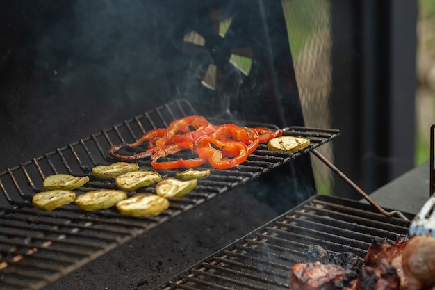 Un barbecue avec des légumes sont grillés sur un feu ouvert.