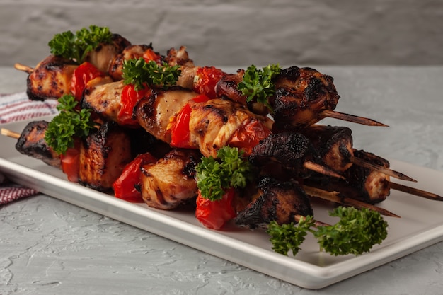 Barbecue de poulet en brochettes avec des légumes sur fond gris