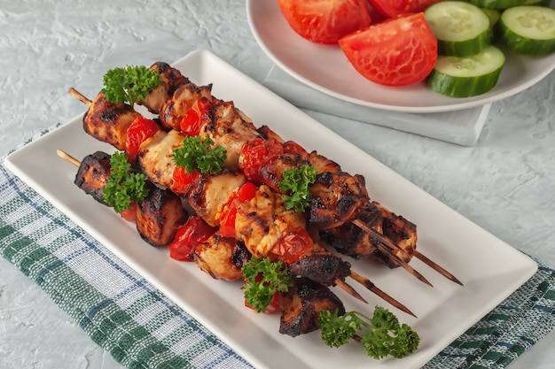 Barbecue de poulet en brochettes avec des légumes sur fond gris