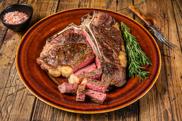 Barbecue rôti porterhouse ou bifteck de viande de bœuf os t sur une plaque rustique sur table en bois. Vue de dessus.