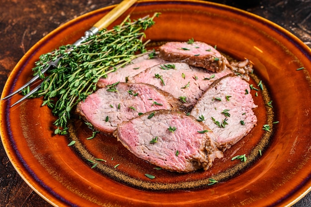 Barbecue de steak de filet de bœuf rôti sur une planche à découper en assiette rustique. Fond sombre. Vue de dessus.