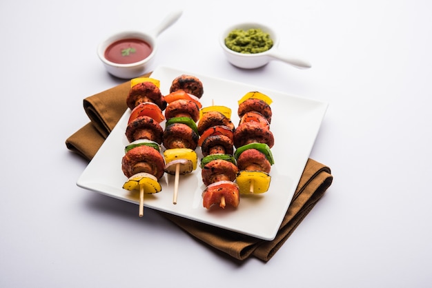 Barbecue ou Tikka aux champignons tandoori, servis dans une assiette avec chutney vert et ketchup. mise au point sélective