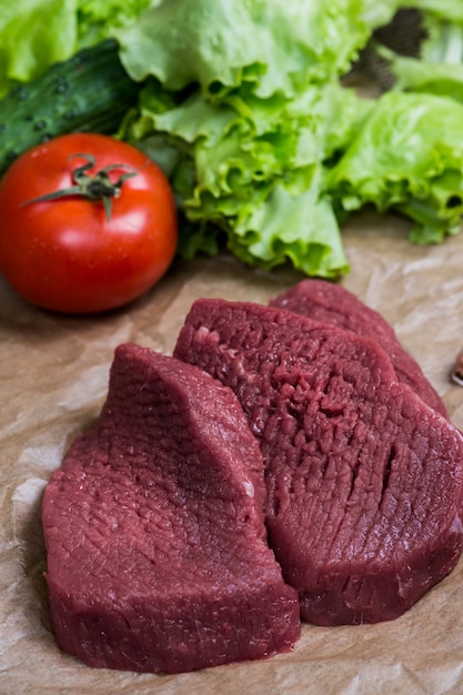 Barbecue de viande crue avec surface en bois de légumes frais. Nourriture, steak, barbecue de boeuf, tomates, poivrons, épices pour la cuisson.