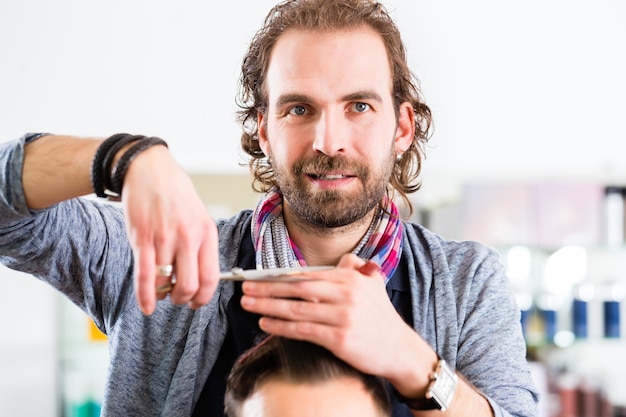 Photo barber coupe les cheveux de l'homme en magasin de coupe de cheveux