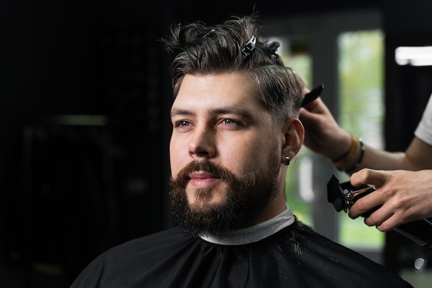 Barber faisant la coiffure pour hipster barbu confiant. Publicité pour salon de coiffure et salon de beauté pour hommes.