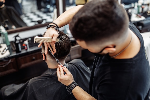 Barber fait une coupe de cheveux et une coiffure dans un salon de coiffure, un salon de beauté. Des cheveux sains.