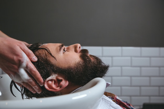 Barber laver les cheveux du client dans le salon de coiffure