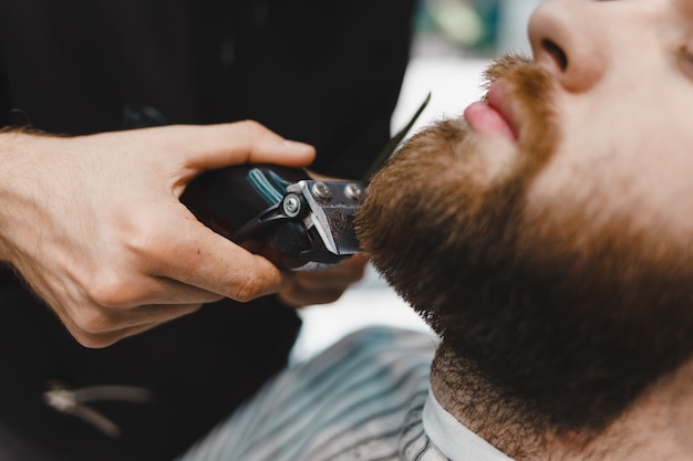 Barber master coupe une barbe à un gros plan de client