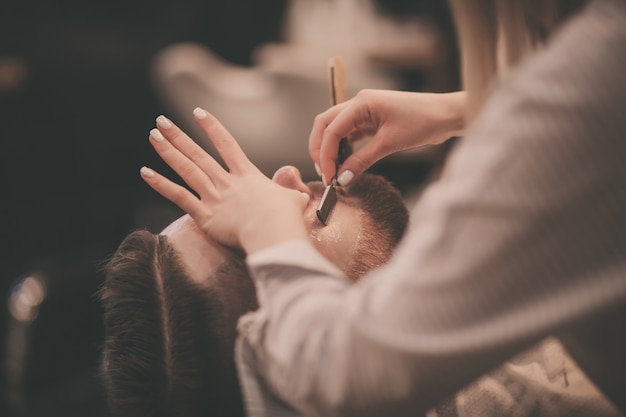 Barber master une fille avec un rasoir dangereux travaille dans un salon de coiffure