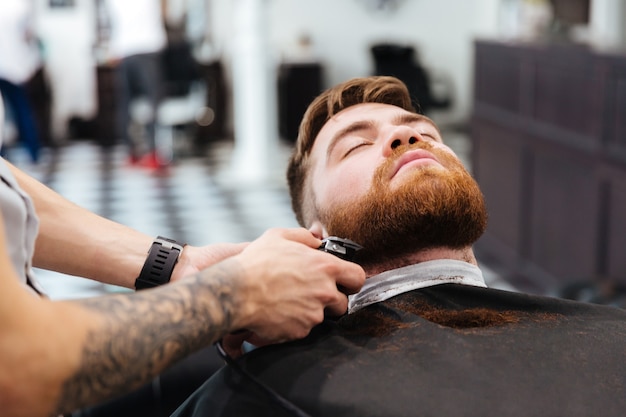 Barber rasant la barbe de son client avec la tondeuse à cheveux