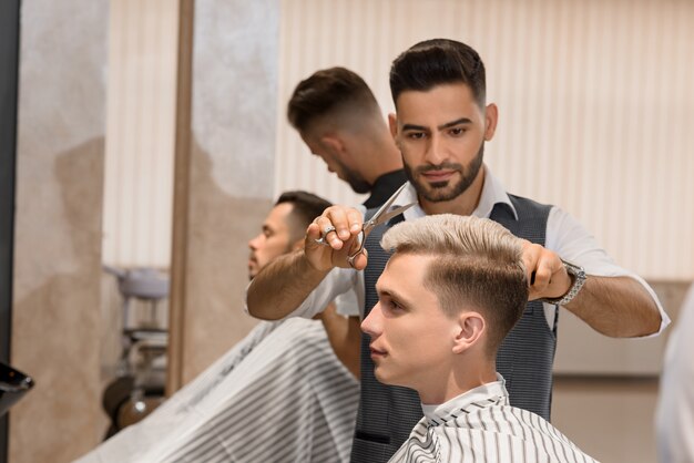 Barber s'est concentré sur le rasage de la barbe de l'homme à l'aide d'un rasoir pointu.