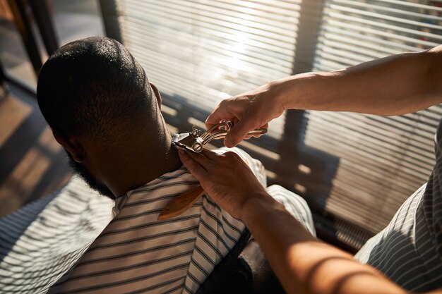 Barbier coupe les cheveux du client avec une tondeuse portable