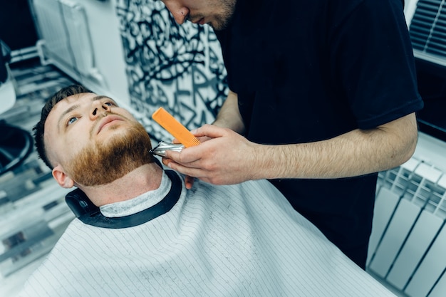 Barbier coupe homme barbu avec machine à raser