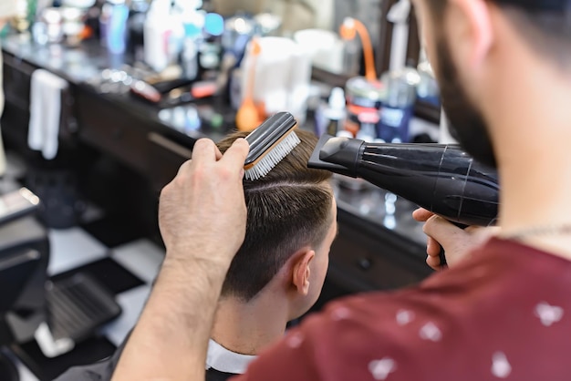 Barbier faisant une coiffure masculine moderne. Salon de coiffure. Man Barber dans le salon de coiffure pour hommes fait des cheveux avec des ciseaux.