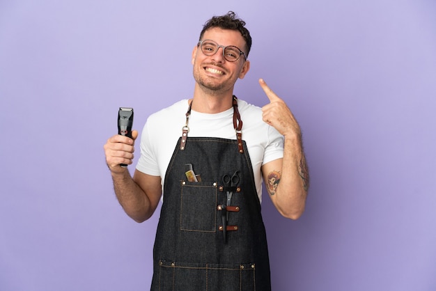 Barbier homme caucasien dans un tablier isolé sur fond violet donnant un geste de pouce en l'air