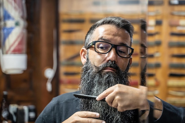 Barbier peignant lui-même sa longue barbe