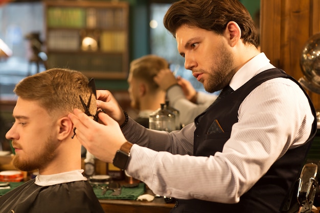 Barbier professionnel travaillant dans son salon de coiffure