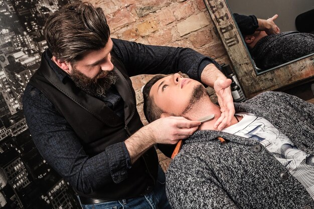 Photo barbier travaillant avec un rasoir droit pour raser la barbe