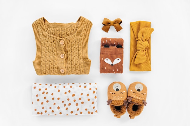 Barboteuse en tricot jaune, serre-tête, chaussettes et jolies chaussons pour bébé. Ensemble de vêtements et accessoires pour nouveau-nés. Mise à plat, vue de dessus