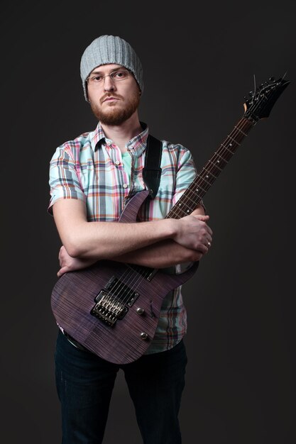 Barbu avec une guitare électrique un musicien créatif dans une chemise à carreaux