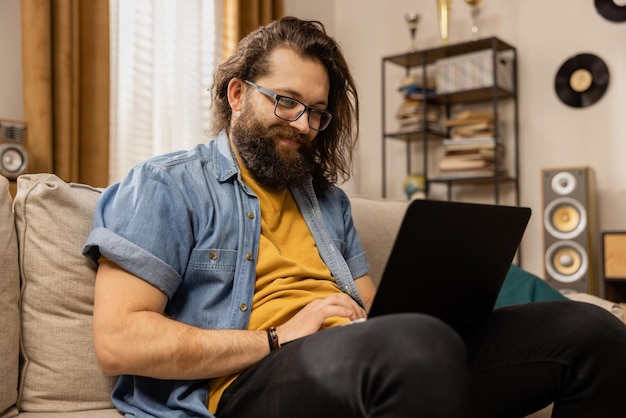 Un barbu parcourt une galerie de photos de vacances sur son ordinateur portable