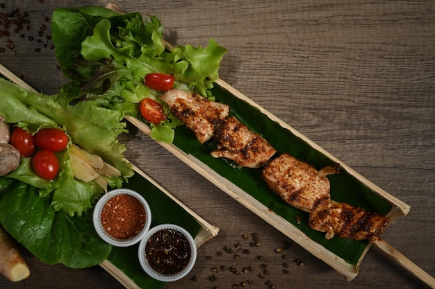 Baril de bambou plat avec brochettes de viande grillée sur table en bois Le barbecue chinois Mala est de la viande ou des légumes grillés avec des épices chaudes et épicées chinoises