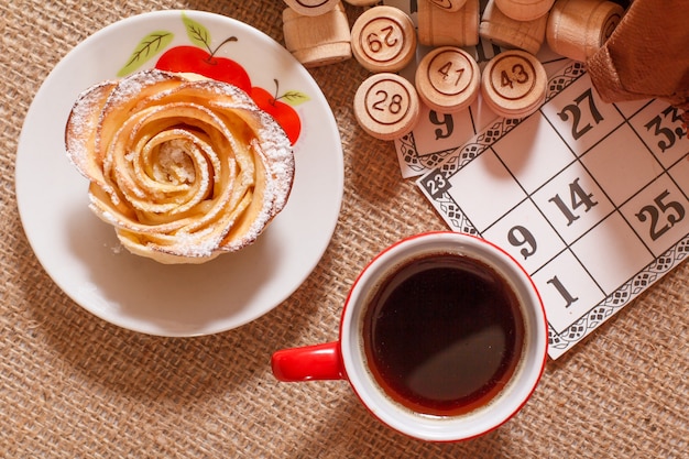 Barils de loto en bois dans une pochette marron et cartes de jeu pour un jeu de loto avec une tasse de café.