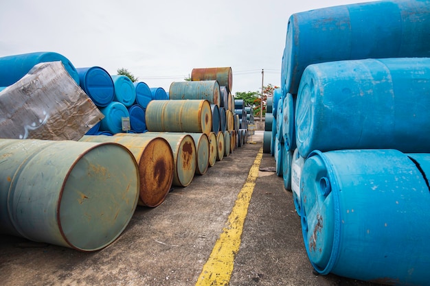 Barils de pétrole vieux fûts chimiques verts et bleus horizontaux empilés.