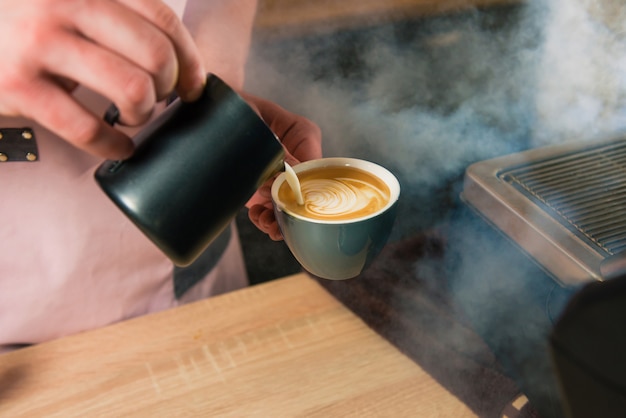 Barista ajoute du lait à l'expresso de manière artistique