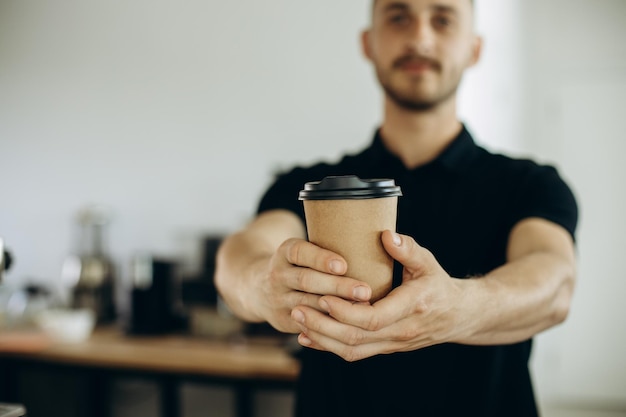 Barista au café tenant une tasse en carton avec du café