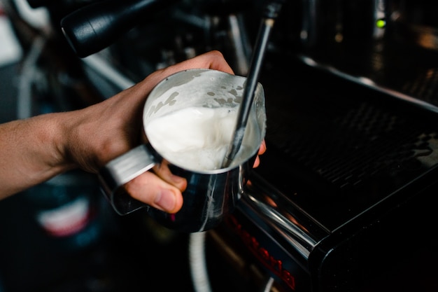 Barista battre la mousse de lait avec la machine