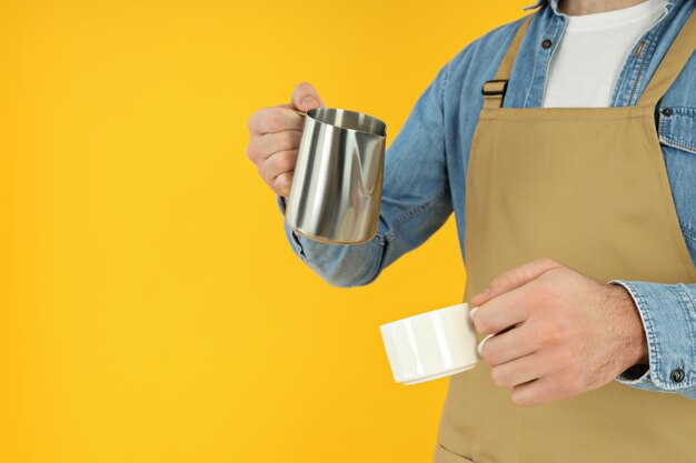 Barista avec cruche et tasse sur fond jaune