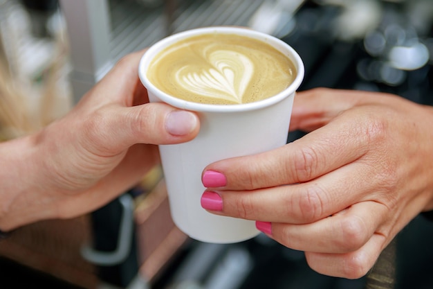 Barista donnant au client une tasse en papier avec du café cappuccino