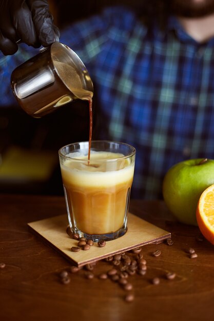 Barista faisant un cocktail de café. Espresso avec jus d'orange et de pomme