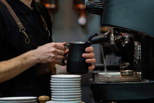 Barista faisant mousser du lait pour faire du café Barista mains devant la machine à café