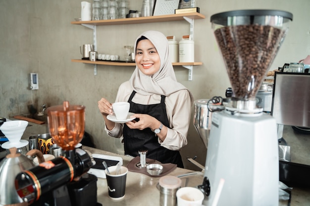 Barista femelle souriant quand se tenir debout sur le café pub