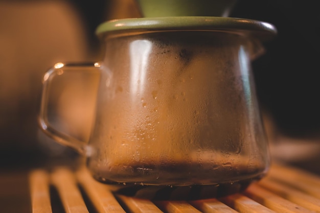 Barista hipster versant de l'eau chaude pour faire du café avec un style goutte à goutte ou filtre dans un café infusion lente pour une boisson aromatisée à la caféine dans une tasse de café noir frais et d'espresso pour le petit déjeuner